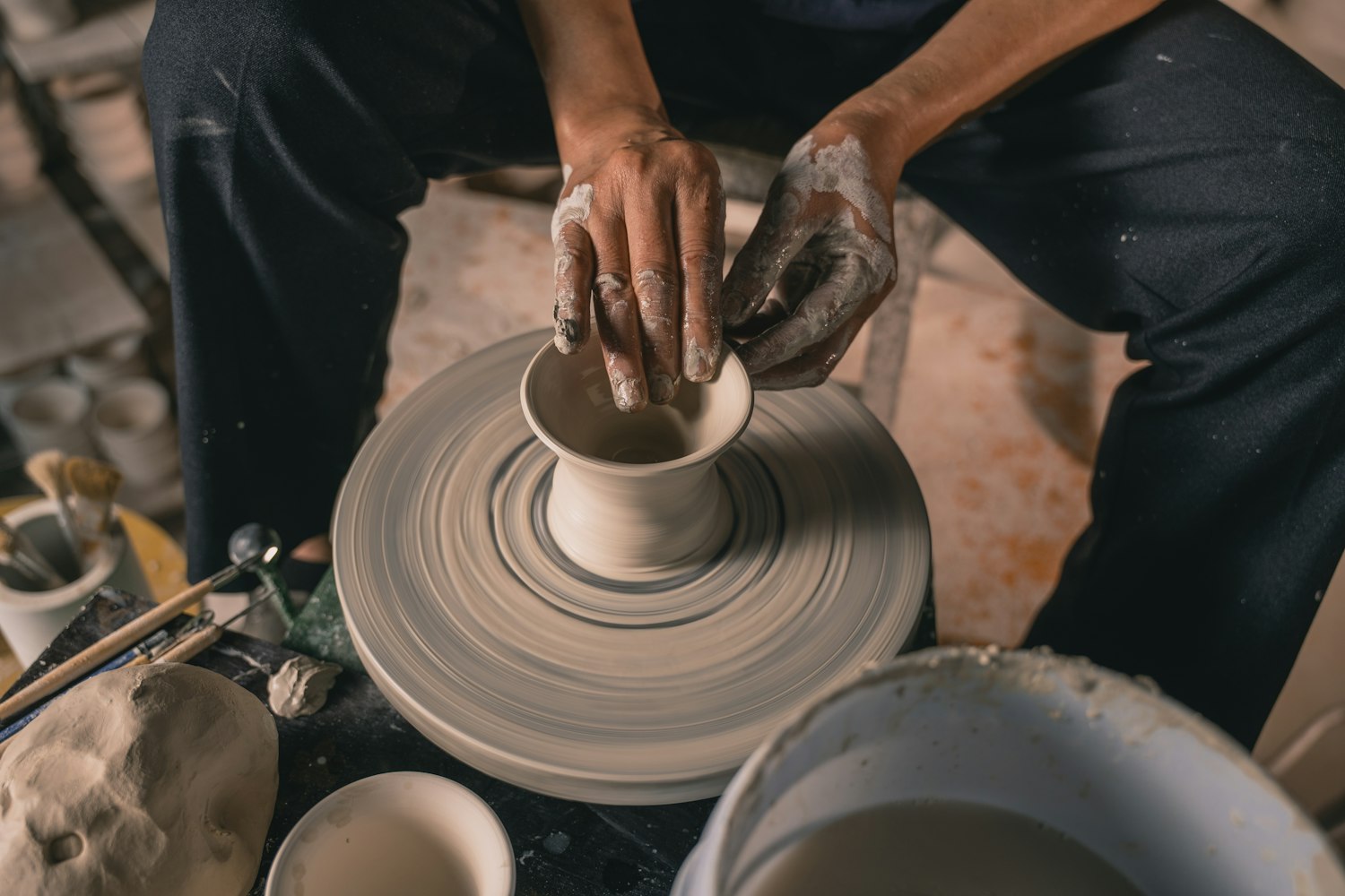 Clay being worked by hand on a pottery wheel